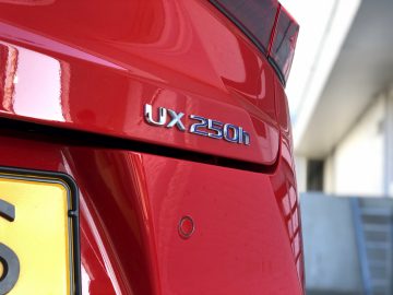 Een rode Lexus UX-badge op een rode auto.