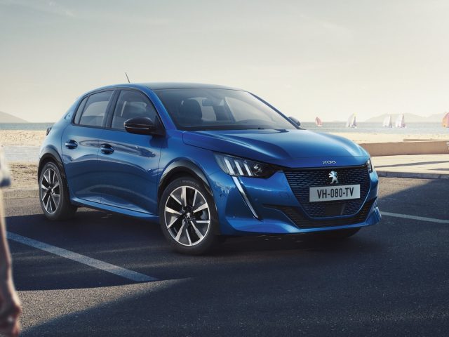 De nieuwe elektrische Peugeot 208 staat geparkeerd voor een strand.