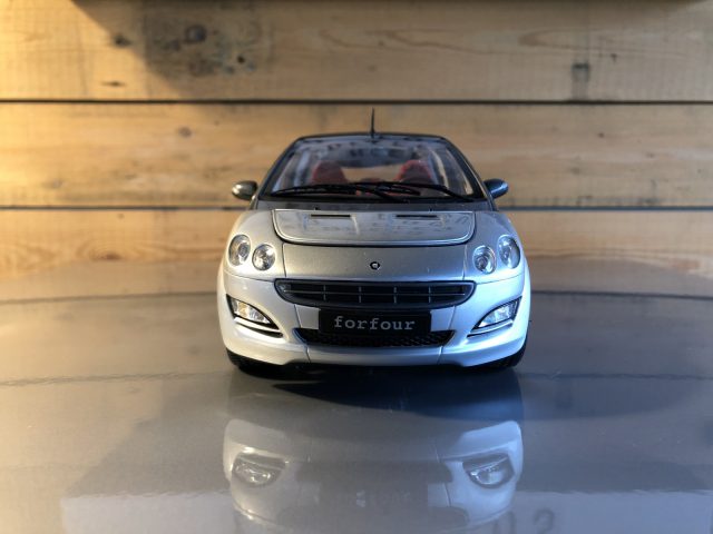 Een slimme zilveren Forfour-speelgoedauto die op een tafel staat.