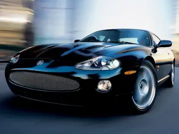 Een zwarte Jaguar-sportwagen rijdt door een stadsstraat.