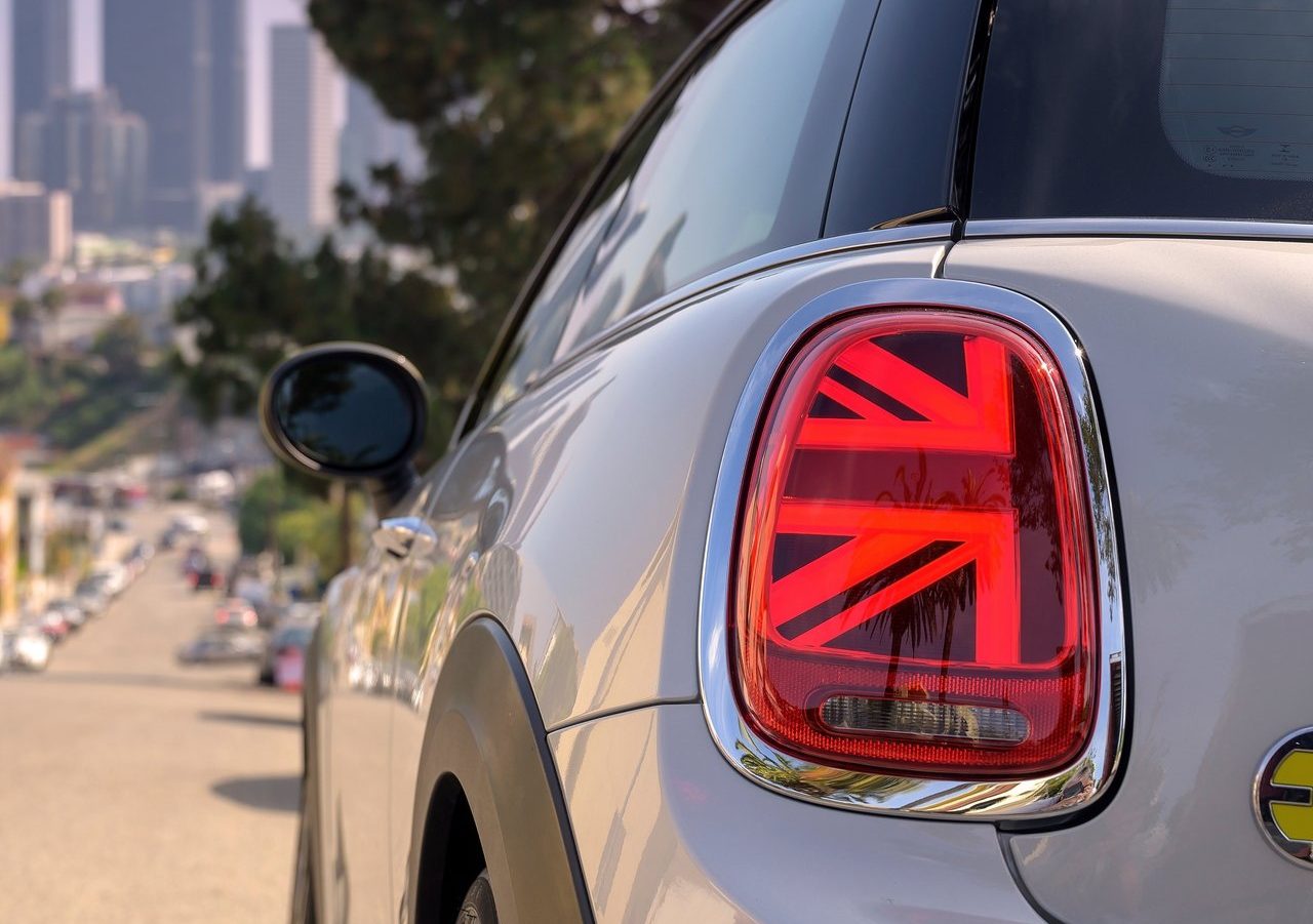 Een witte elektrische auto mini-cooper met een Britse vlag op het achterlicht.