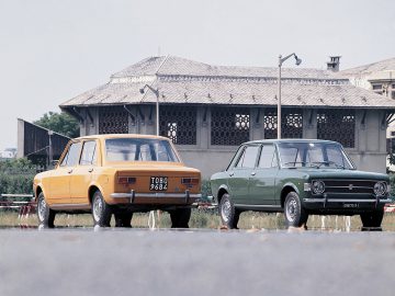 Twee oude Fiat 128-auto's geparkeerd naast elkaar.