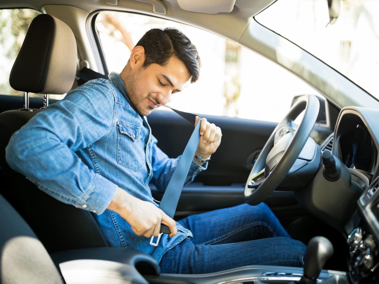 Een man zit in zijn auto met zijn veiligheidsgordel afgesteld, klaar voor een eersteklas vertrek.