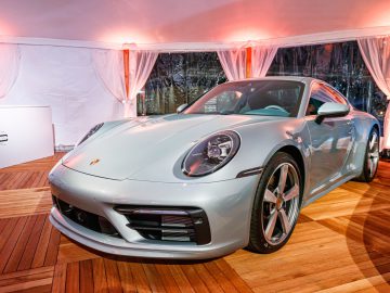Een zilveren Porsche 911 staat geparkeerd op een houten vloer.
