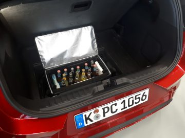 Een rode Ford met een koelbox in de kofferbak.