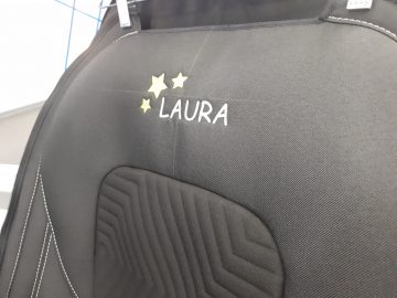 Een zwarte Ford design autostoel met het woord Laura erop.