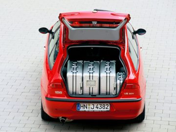 Een rode Alfa Romeo 156 met een kofferbak vol bagage.