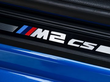 De BMW M2 CS-badge op een blauwe auto.