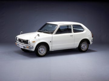 Een witte Honda Civic staat geparkeerd op een grijze achtergrond.