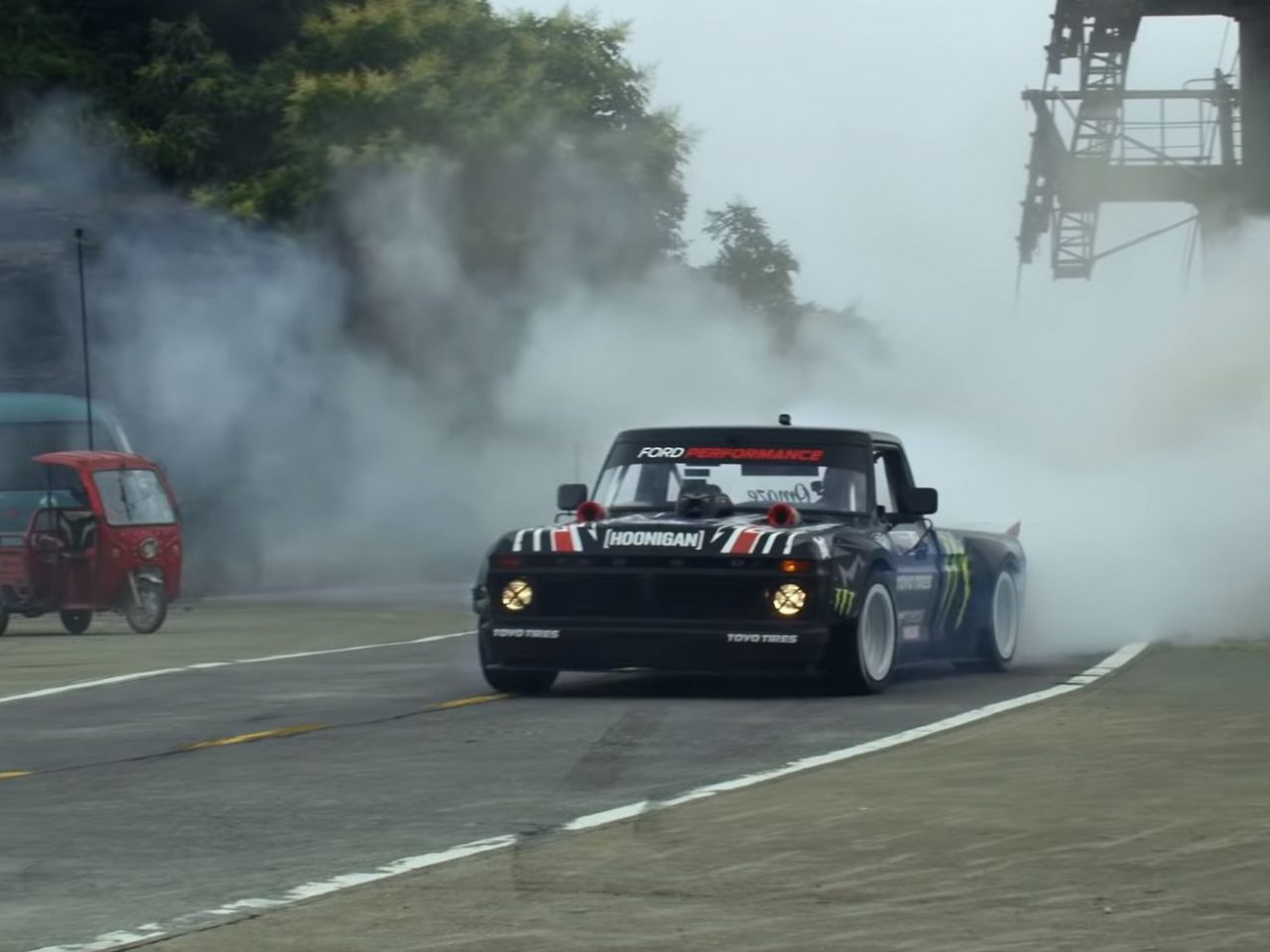 Een vrachtwagen die over een weg rijdt waar rook uit komt, bestuurd door Ken Block.