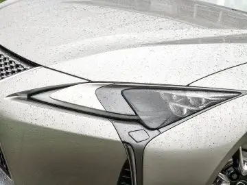 De voorkant van een zilverkleurige Lexus LC 500h met regen erop.