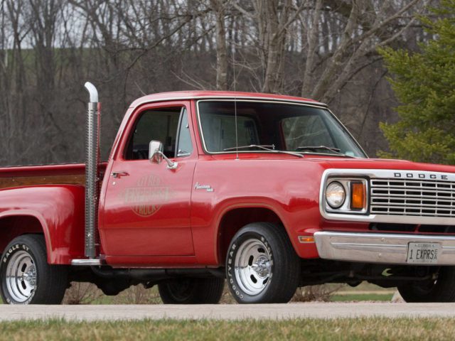 Een rode Dodge-pick-up staat voor een boom geparkeerd.