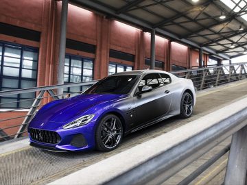 Een blauwe Maserati GranTurismo-sportwagen staat geparkeerd op een brug.