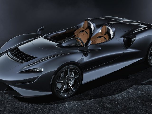 In een donkere kamer wordt een McLaren Elva-sportwagen getoond.