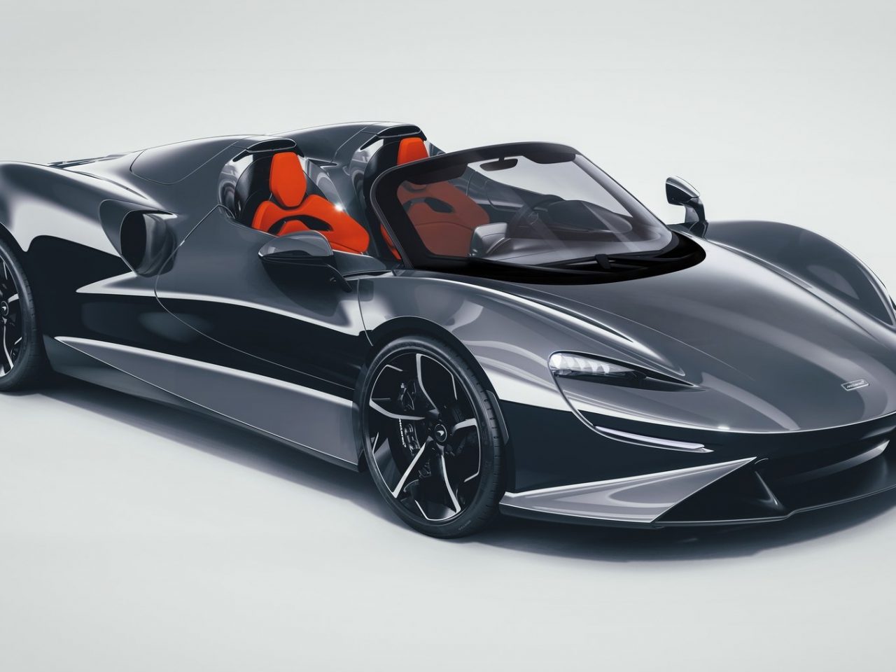 Een zwart-oranje McLaren Elva-sportwagen op een witte achtergrond.