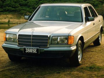 Een zilveren Mercedes-Benz S-Klasse, uitgerust met airbags, geparkeerd aan de kant van een onverharde weg.