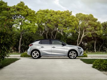 Voor een huis staat een zilverkleurige Opel Corsa geparkeerd.