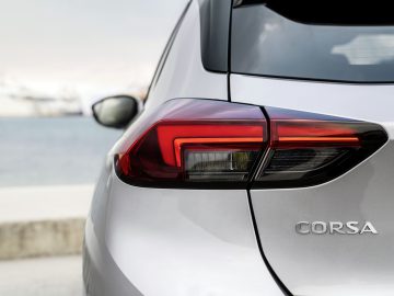 De achterkant van een zilveren Opel Corsa geparkeerd vlakbij het water.