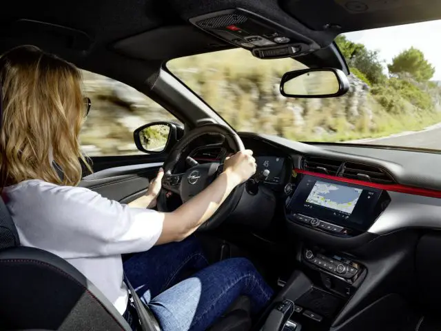 Een vrouw bestuurt een Opel Corsa op een weg.