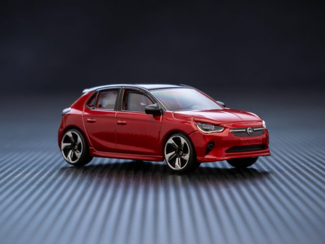 Een rode Opel Corsa speelgoedauto op een zwarte achtergrond.
