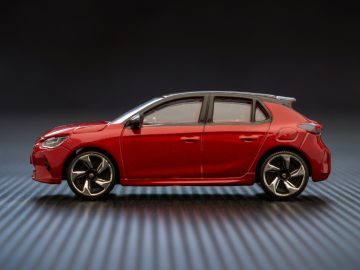 Een rode Opel Corsa speelgoedauto op een zwarte achtergrond.