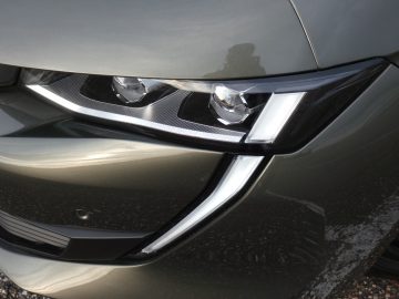 Een close-up van de koplampen van een grijze Peugeot 508.