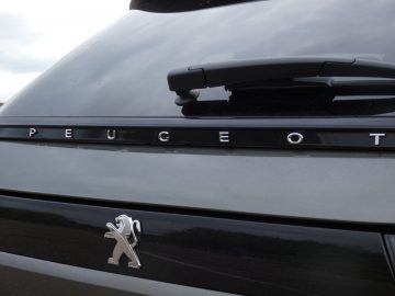 Een zwarte Peugeot 508 Rogue met het Peugeot-logo achterop de auto.