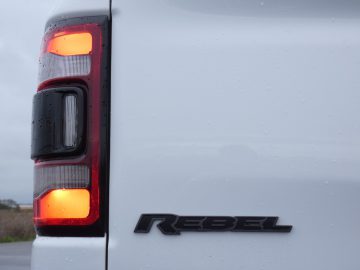 Het achterlicht van een witte RAM-truck met het woord rebel erop.