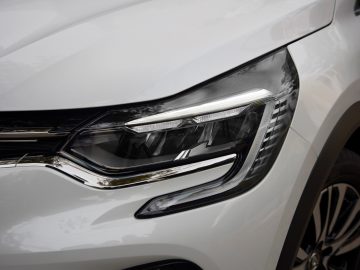 Een close-up van de koplampen van een witte Renault Captur.
