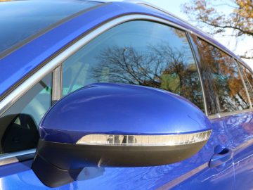 De achteruitkijkspiegel van een blauwe Volkswagen Passat Variant.