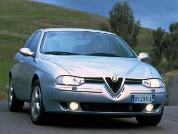 Een zilveren Alfa Romeo 156 die over een weg rijdt.