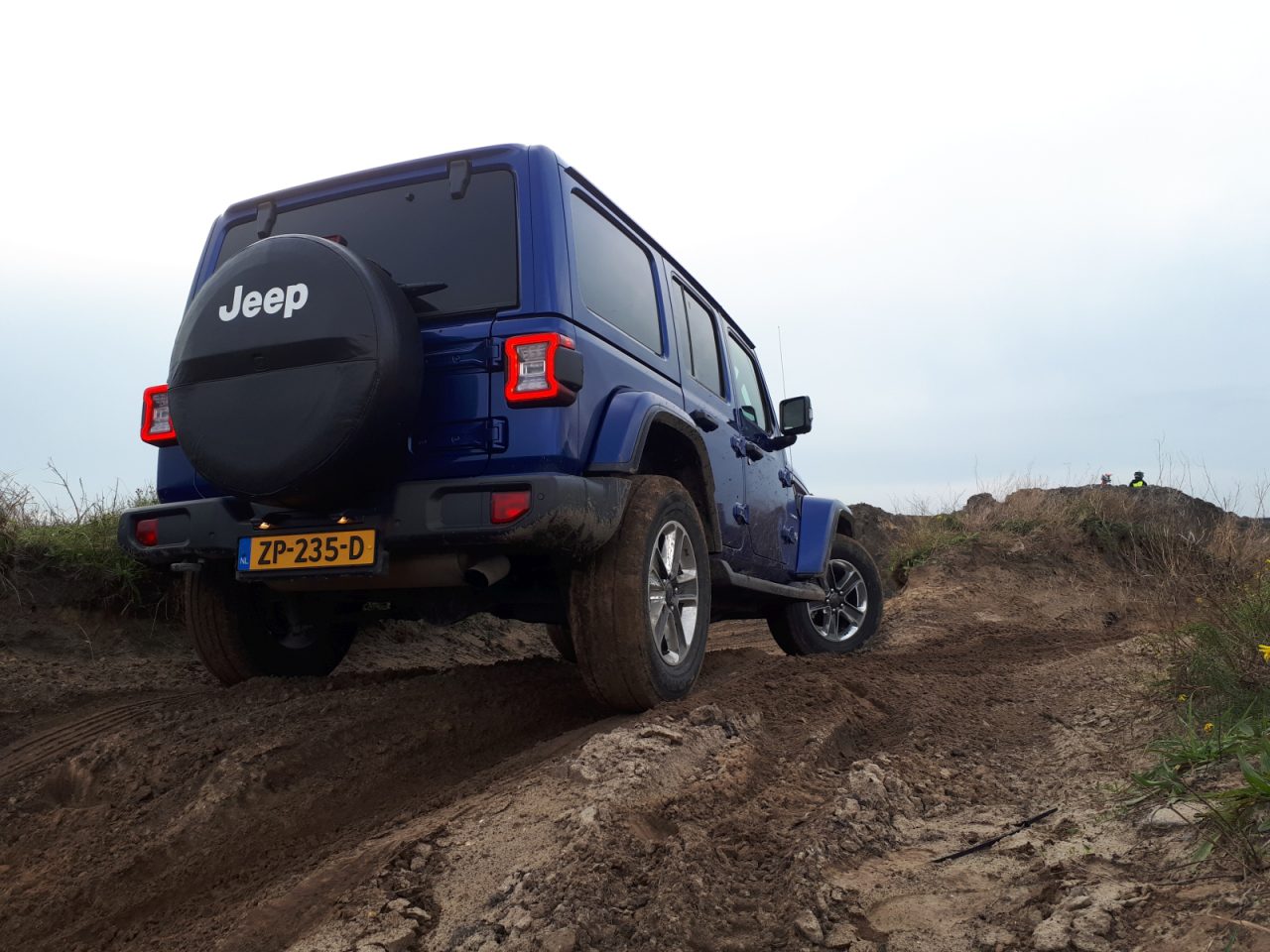 Een blauwe jeep op een onverharde weg, model autojaar 2019.