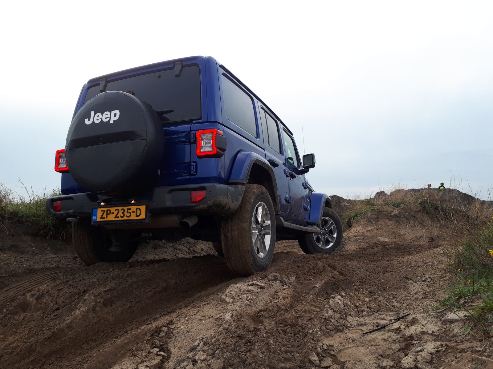 Een blauwe jeep op een onverharde weg, model autojaar 2019.
