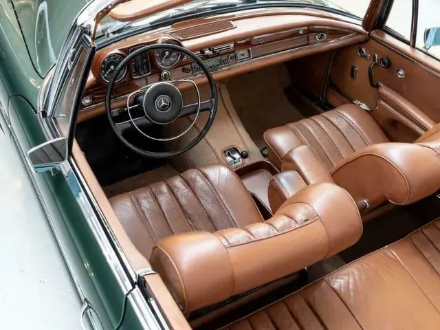 Het interieur van een klassieke Mercedes-Benz-auto met lederen stoelen en stuurwiel.