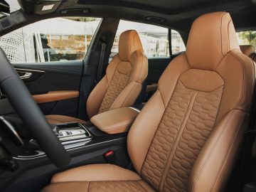 Het interieur van een Audi RS Q8 met bruin lederen stoelen.
