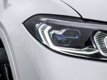 De koplampen van een witte BMW X7.