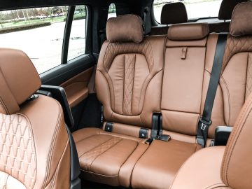 Het interieur van een BMW X7 met bruin lederen stoelen.