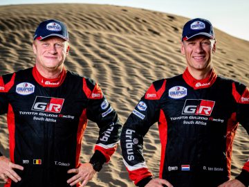 Bernhard ten Brinke en een andere man poseren voor een zandduin.