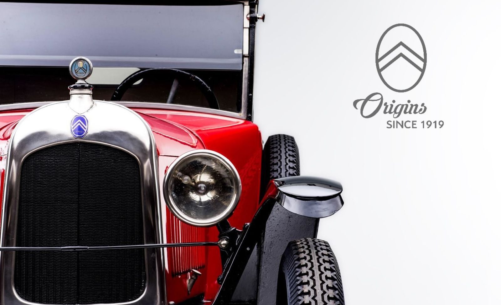 Een oude rode Citroën-auto met een logo erop.