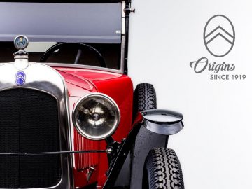 Een oude rode Citroën-auto met een logo erop.