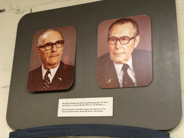 Twee foto's van mannen met een bril aan de muur in het DAF Museum.