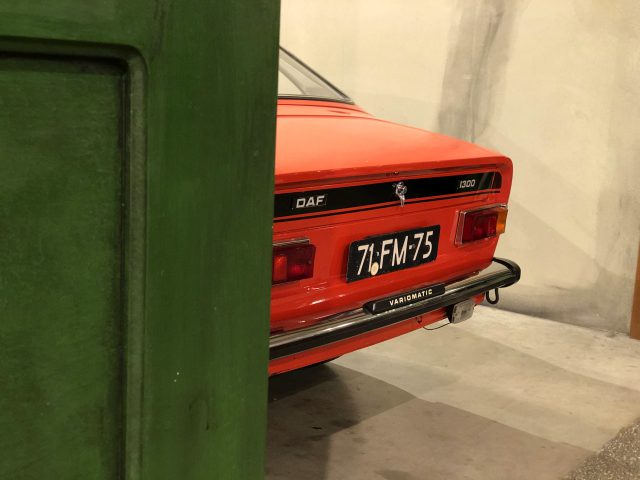 Een rode auto geparkeerd in de garage van het DAF Museum.