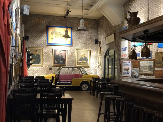 Een bar met krukken en een DAF Museumauto aan de muur.