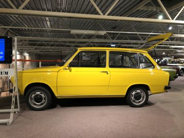 Een gele auto geparkeerd in de garage van het DAF Museum.