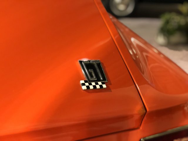 Een close-up van een geruite badge op een oranje auto in het DAF Museum.