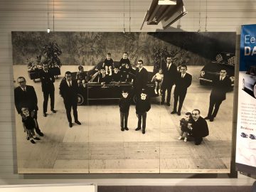 Een zwart-witfoto van een groep mensen poserend voor een auto in het DAF Museum.