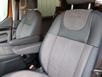 Binnenaanzicht van een Ford Transit Custom MS-RT met twee voorstoelen met een logo op de hoofdsteunen en contrasterende stiksels.