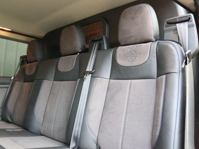 Lederen en suède Ford Transit Custom MS-RT autostoelen met hoofdsteunen en veiligheidsgordels in een modern voertuiginterieur.