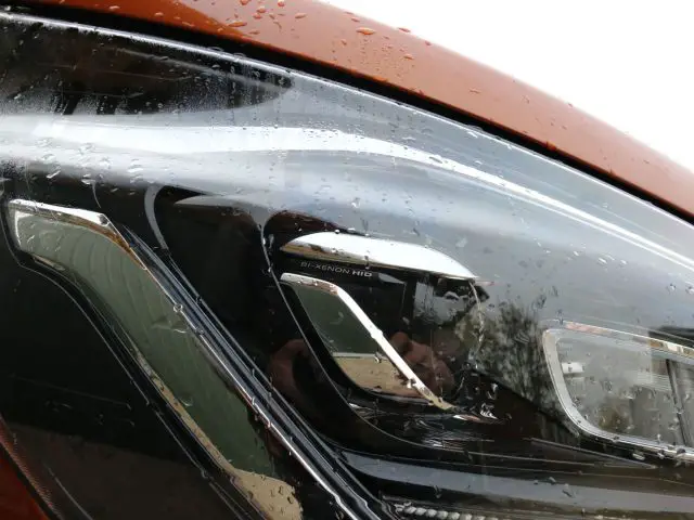 Close-up van een natte Ford Transit Custom MS-RT-koplamp met regendruppels erop.