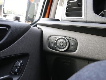 Binnenaanzicht van een Ford Transit Custom MS-RT, gericht op het op de deur gemonteerde bedieningspaneel voor zijspiegelverstellingen en raambediening.